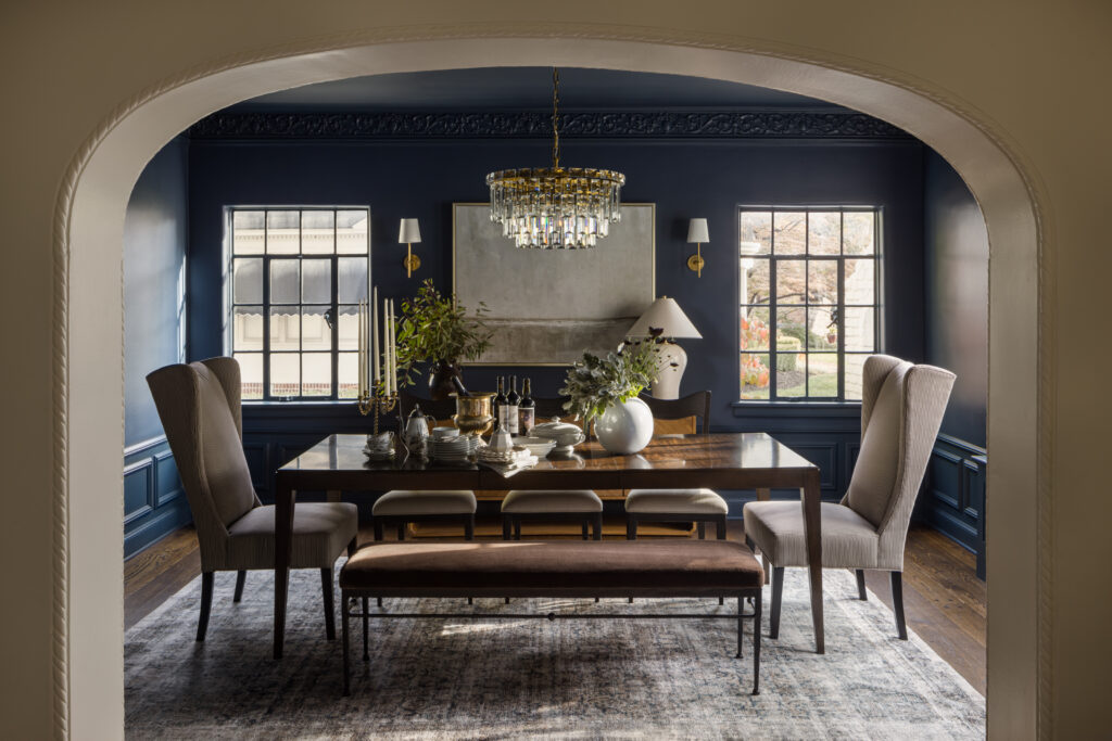 Arched opening into dining room colored drenched in moody blue.